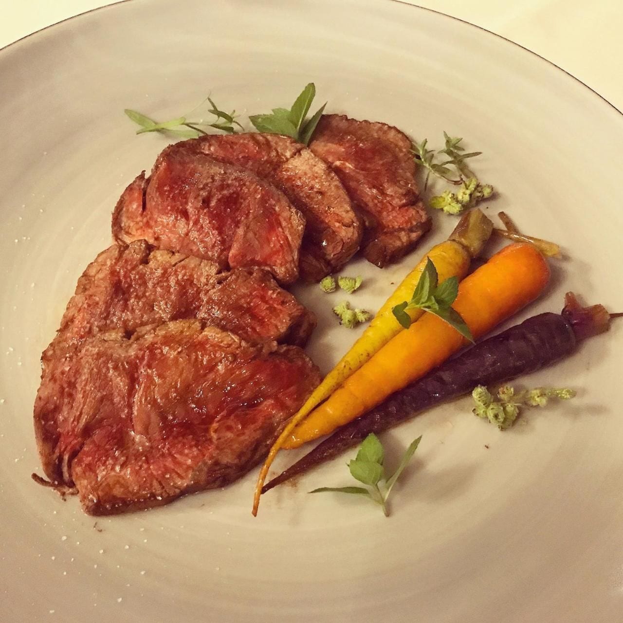 A plate with sliced meat and vegetables.