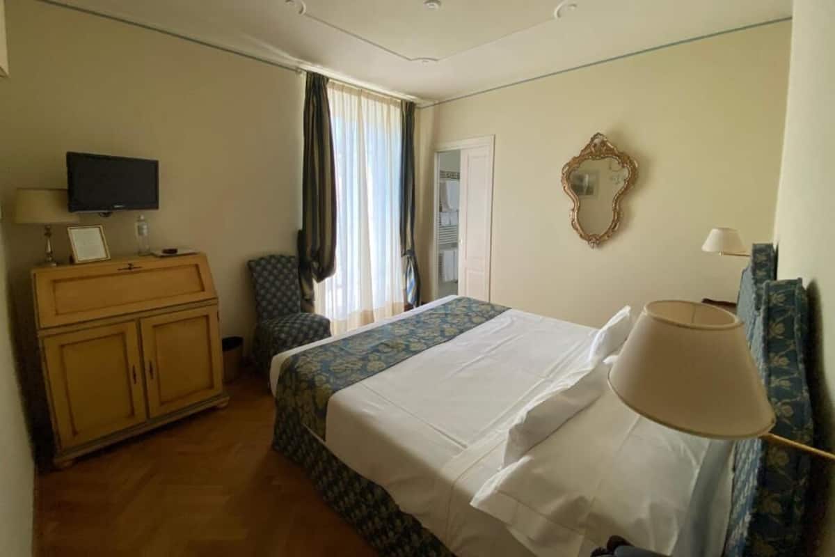 Une chambre d’hôtel comprenant un lit, une télévision, une armoire, une chaise et un miroir.