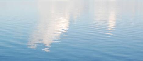 Una superficie acuática tranquila que refleja el cielo y las nubes con claridad.