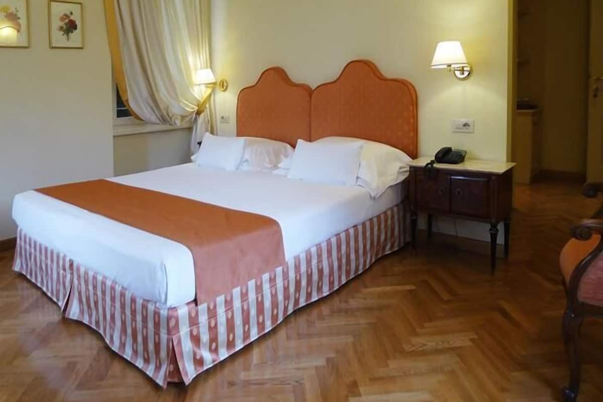 Un lit bien fait, avec une tête de lit en bois, une table de chevet avec une lampe et une chaise.