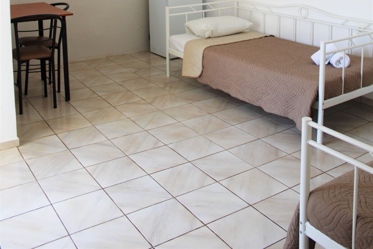 A small, clean room with a bed, a desk, and a chair.