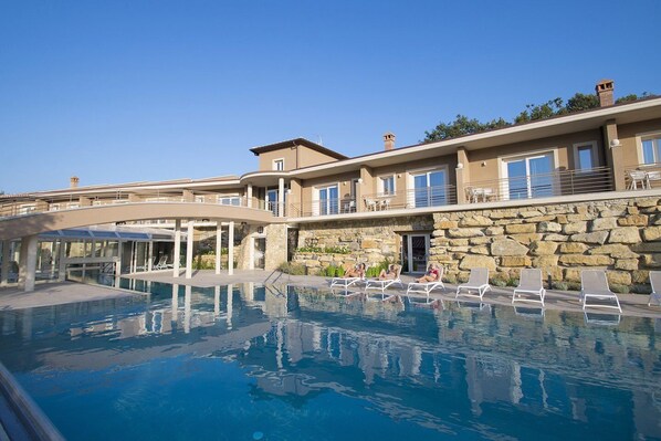 Alberca techada, alberca al aire libre y camastros