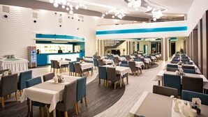 A spacious restaurant with multiple dining areas, a bar, and a staircase leading to an upper level. - Grand Laola Spa (Rewal)