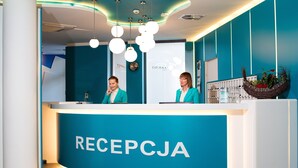 A reception desk with a teal color scheme and the word "RECEPCJA" on it. - Grand Laola Spa (Rewal)
