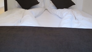 A bed with white bedding and two black pillows. - Apartment Gurguliat Sofia (Sofia)