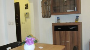 A dining area with a wooden table, black chairs, a vase with flowers, and a wooden cabinet with glass doors. - Apartment Gurguliat Sofia (Sofia)