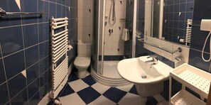 A bathroom with a white toilet, a shower area, and a sink. - Hotel Bella (Jelenia Gora)