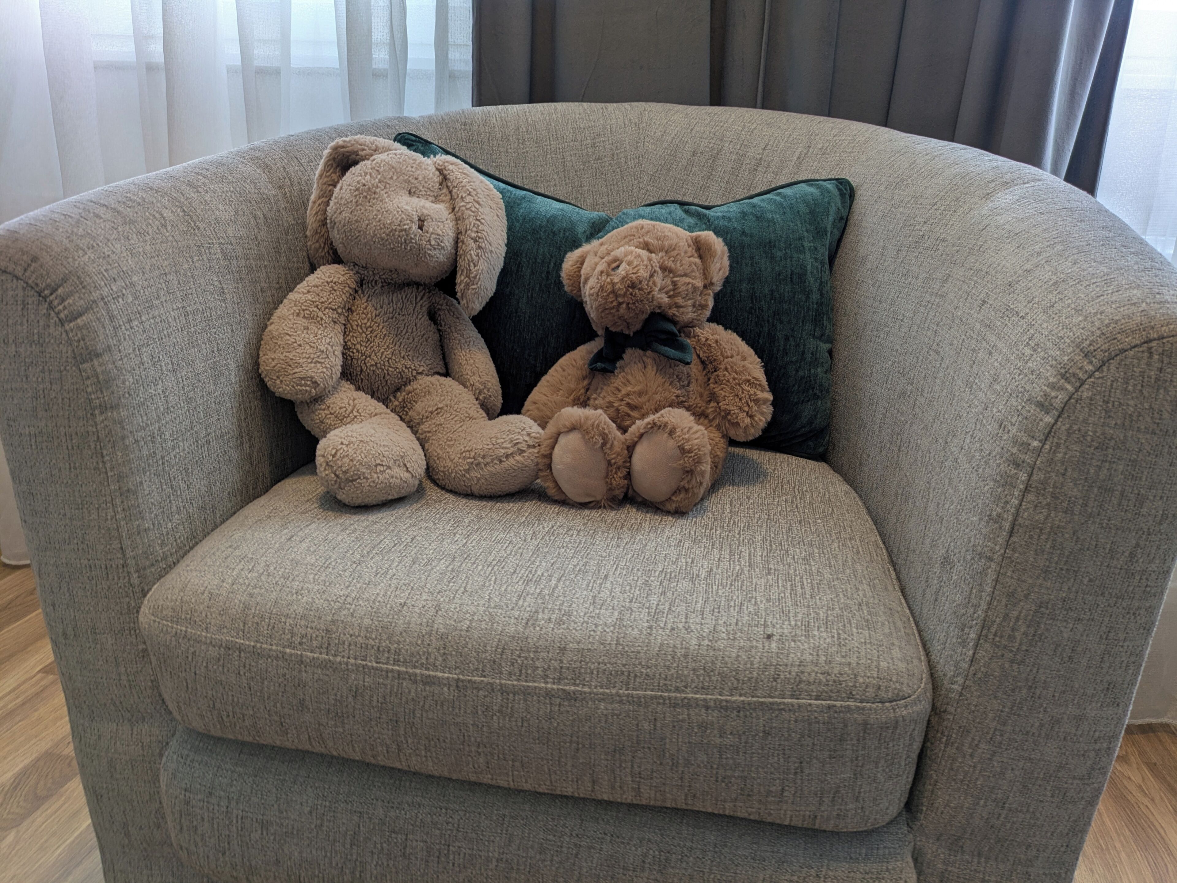 Een grijze bank met twee bruine teddyberen er bovenop.