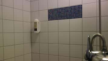 Een betegelde douche met een handdouche en een digitaal display voor de watertemperatuur.