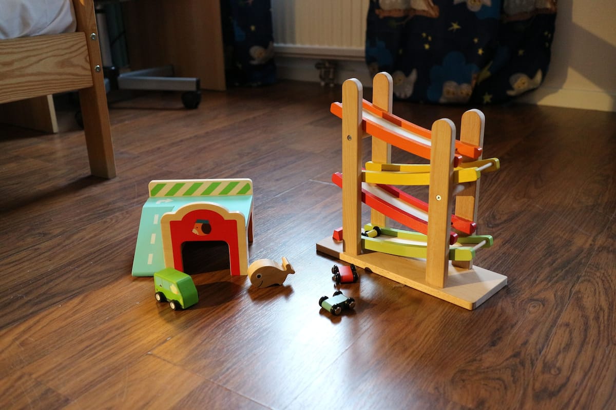 A wooden play structure with a slide and a small building.