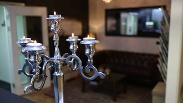 Un candelabro con múltiples luces similares a velas en una habitación que tiene un sofá y un televisor al fondo.