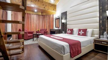 A spacious bedroom with a large bed, wooden ceiling, and a red chair.