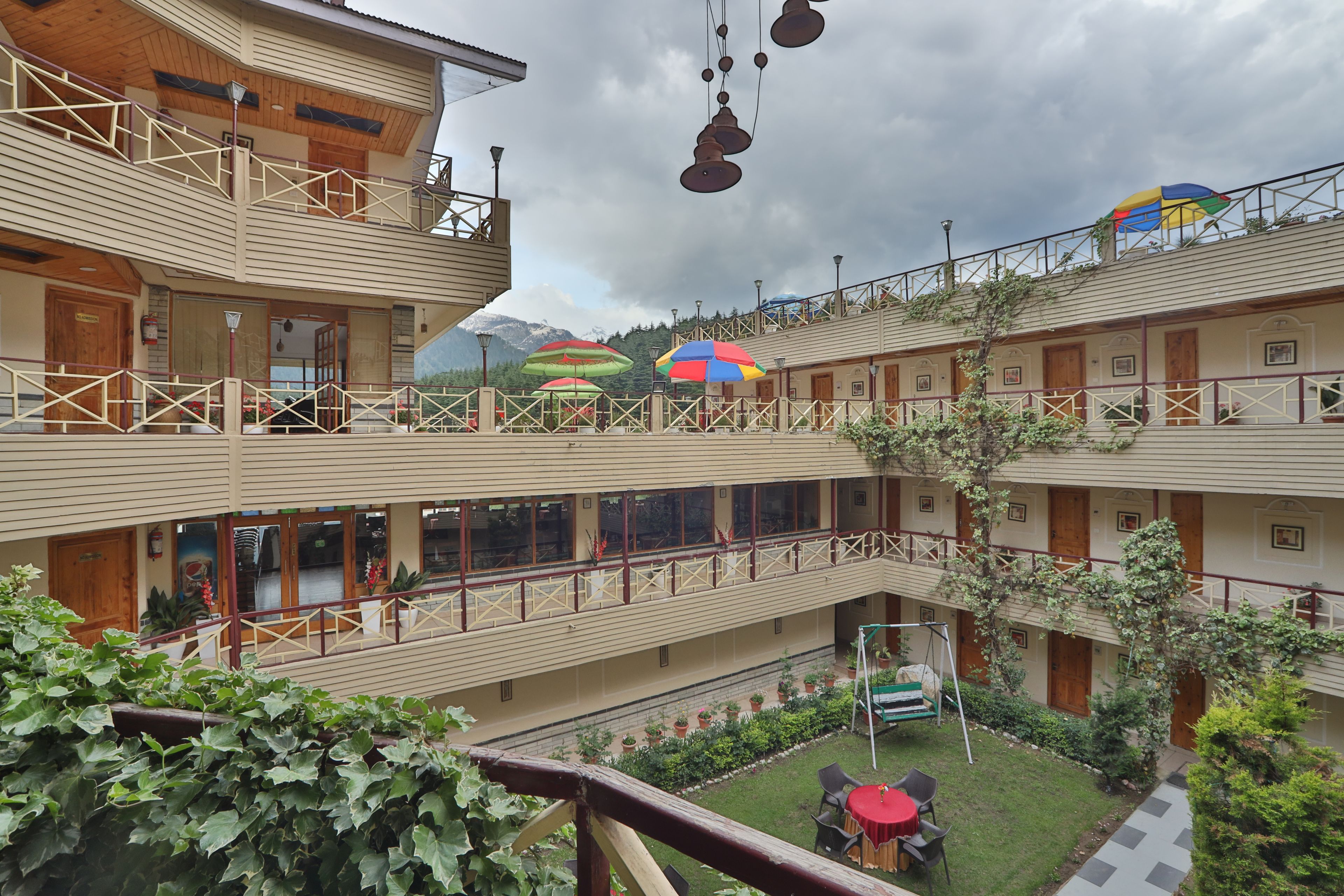 A multi-story hotel with balconies, outdoor seating, and a garden area.