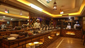 Restaurante com balcão de tijolos, diversas estações de serviço e chefs uniformizados.