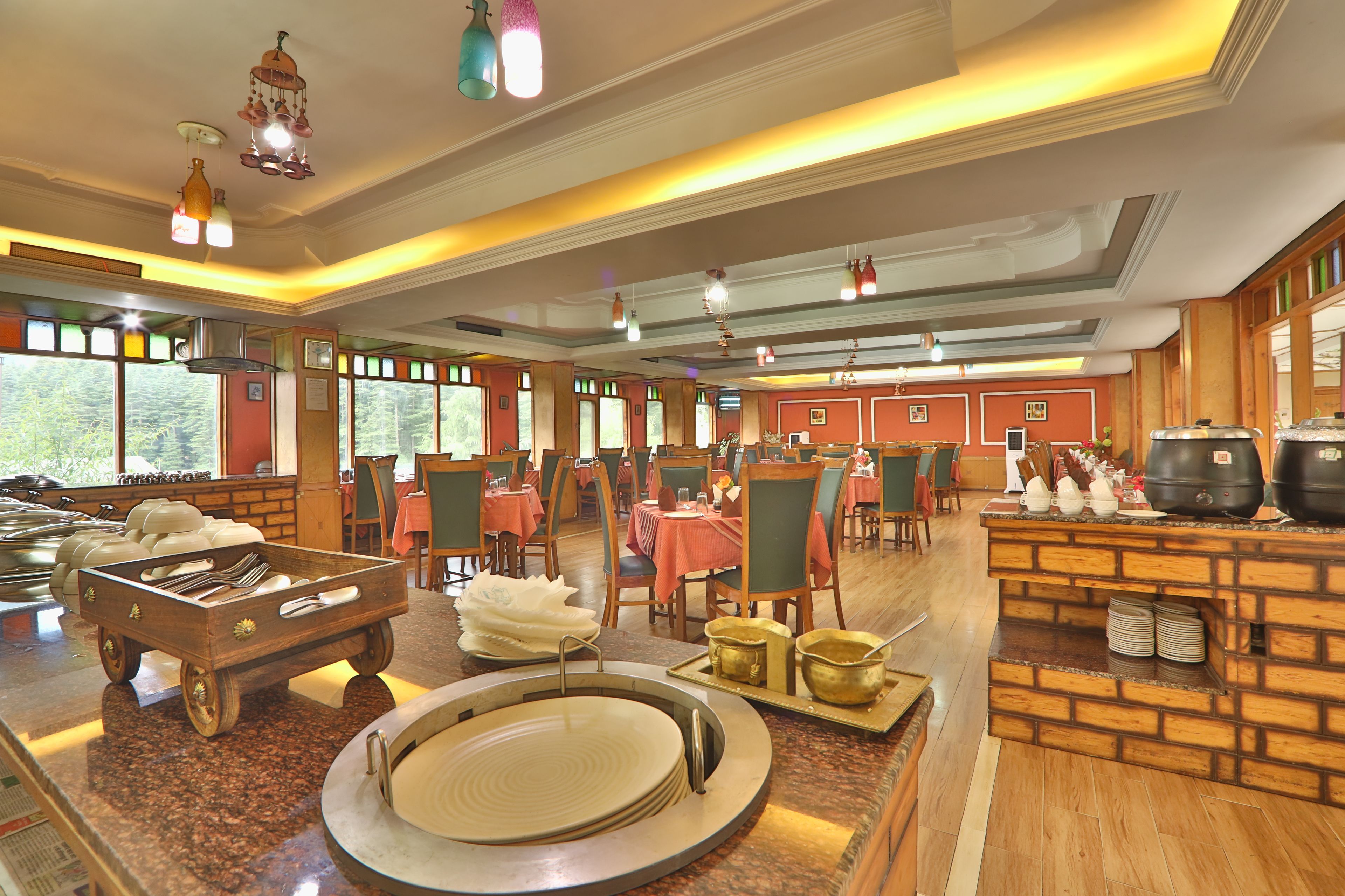 A restaurant with a buffet setup, wooden furniture, and a brick accent wall.