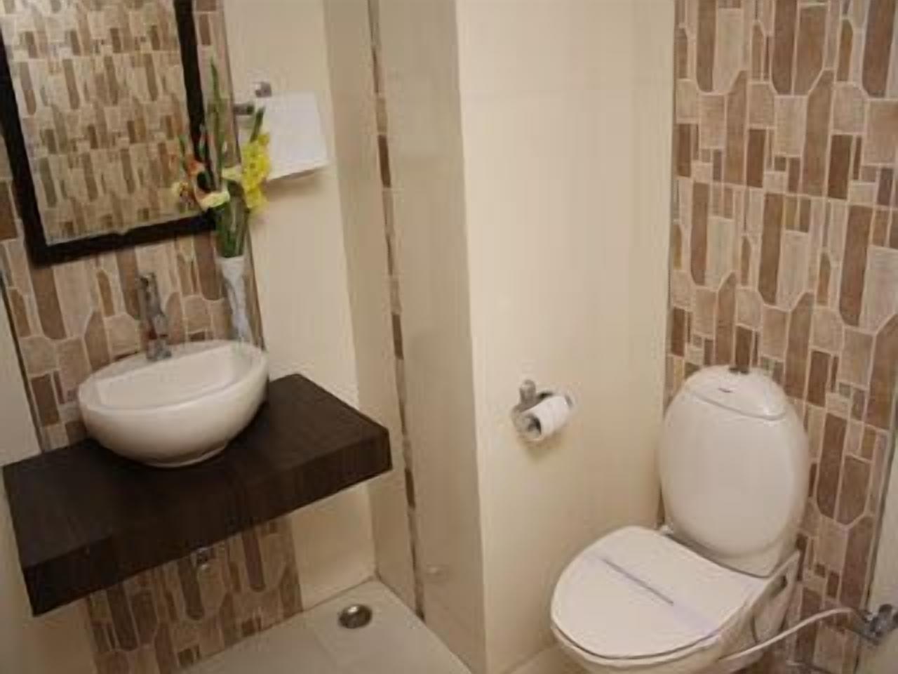 Un baño con lavamanos blanco, inodoro y espejo.