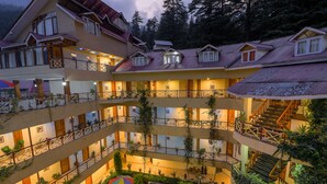 Um hotel com vários andares, varandas, plantas em vasos e um pátio central.