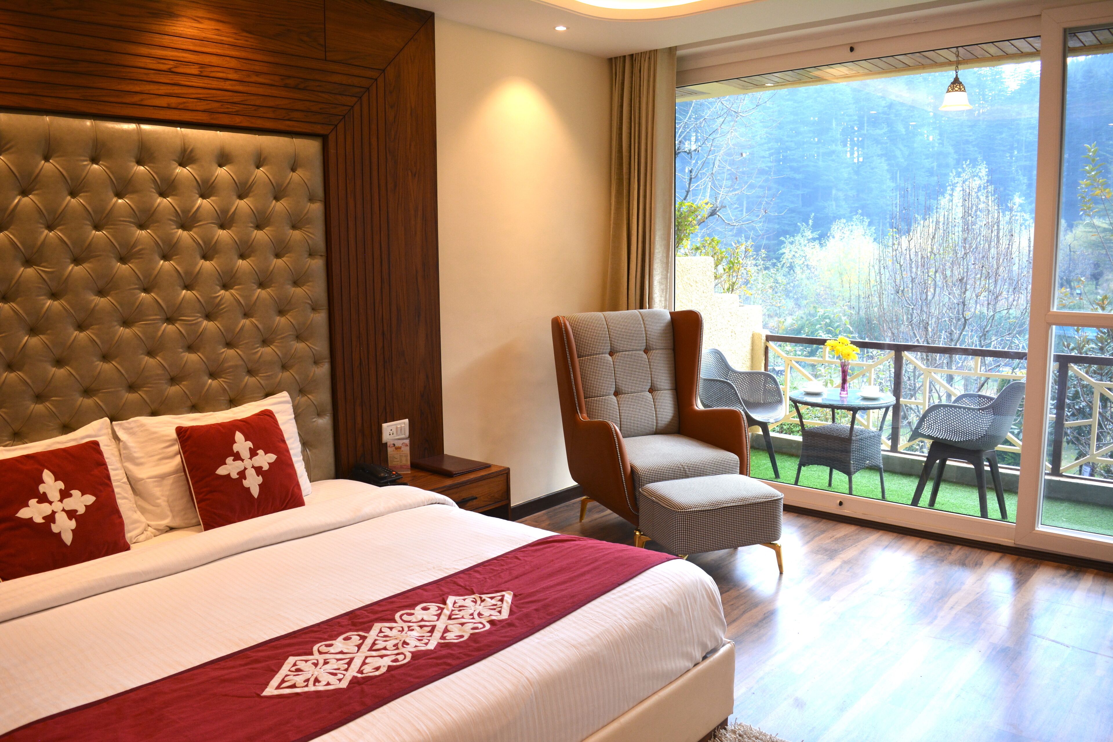 Habitación de hotel con una cama grande, una silla y un balcón con mobiliario exterior.