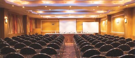 A conference room with rows of chairs, a presentation screen, and a podium.