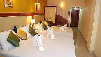 Habitación de hotel con dos camas, cada una con ropa de cama y almohadas blancas, una lámpara de noche y un cuadro en la pared.