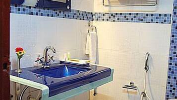 A bathroom with a blue sink, a mirror, a towel rack, and a shower.