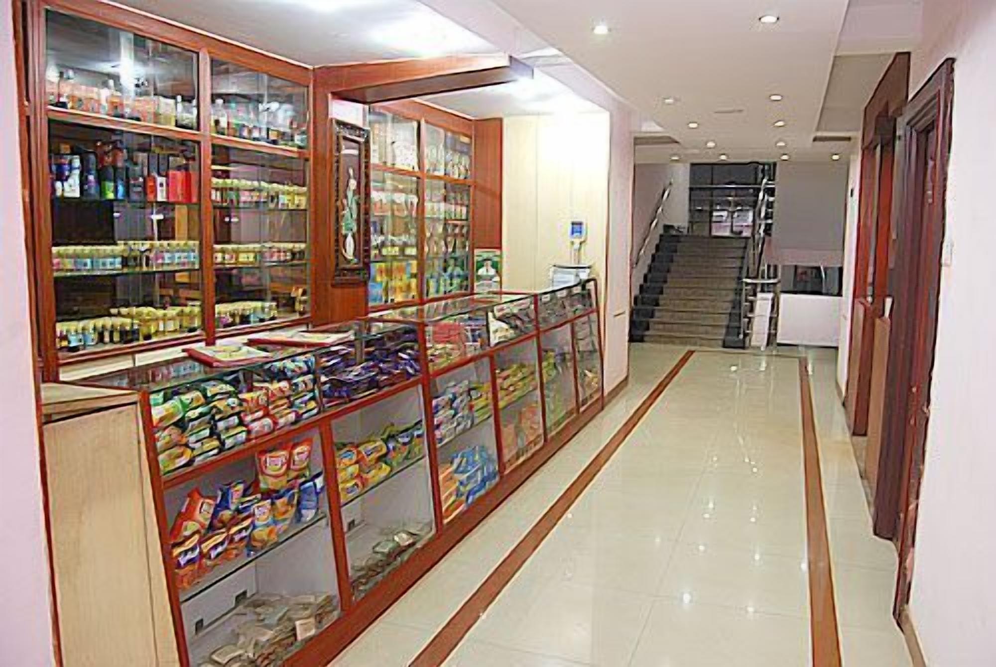 Um corredor com vitrines de vidro repletas de lanches e bebidas, que leva a uma escadaria.