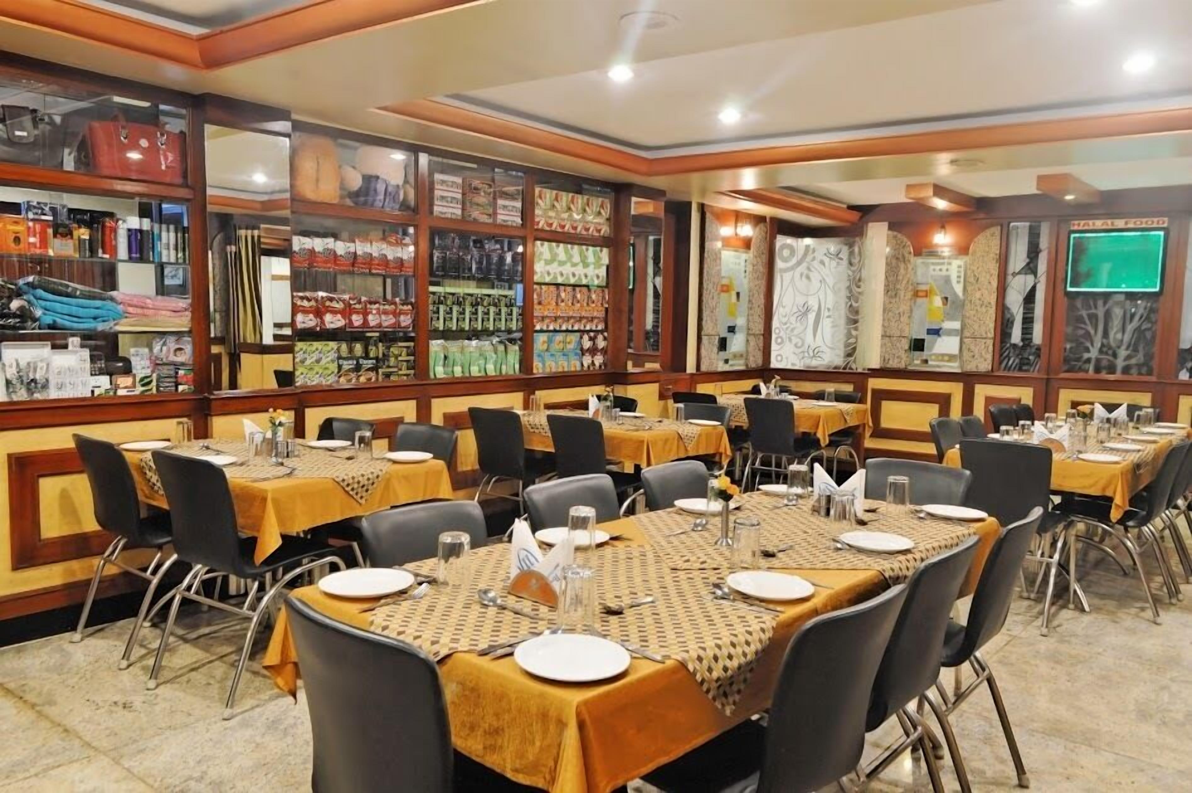 Un restaurante con varias mesas dispuestas para comer, cada una con mantel amarillo y sillas negras.