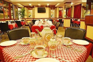 A dining area with tables set for tea service, featuring teapots, cups, and saucers.