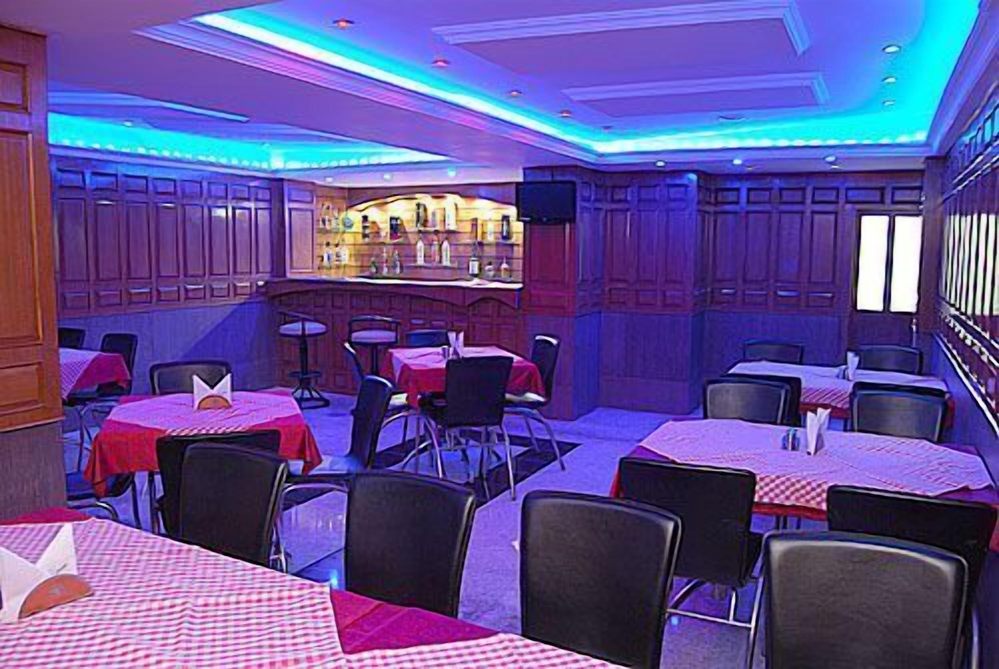 Un restaurant amb diverses taules i caires, una zona de bar i una pantalla de televisió.