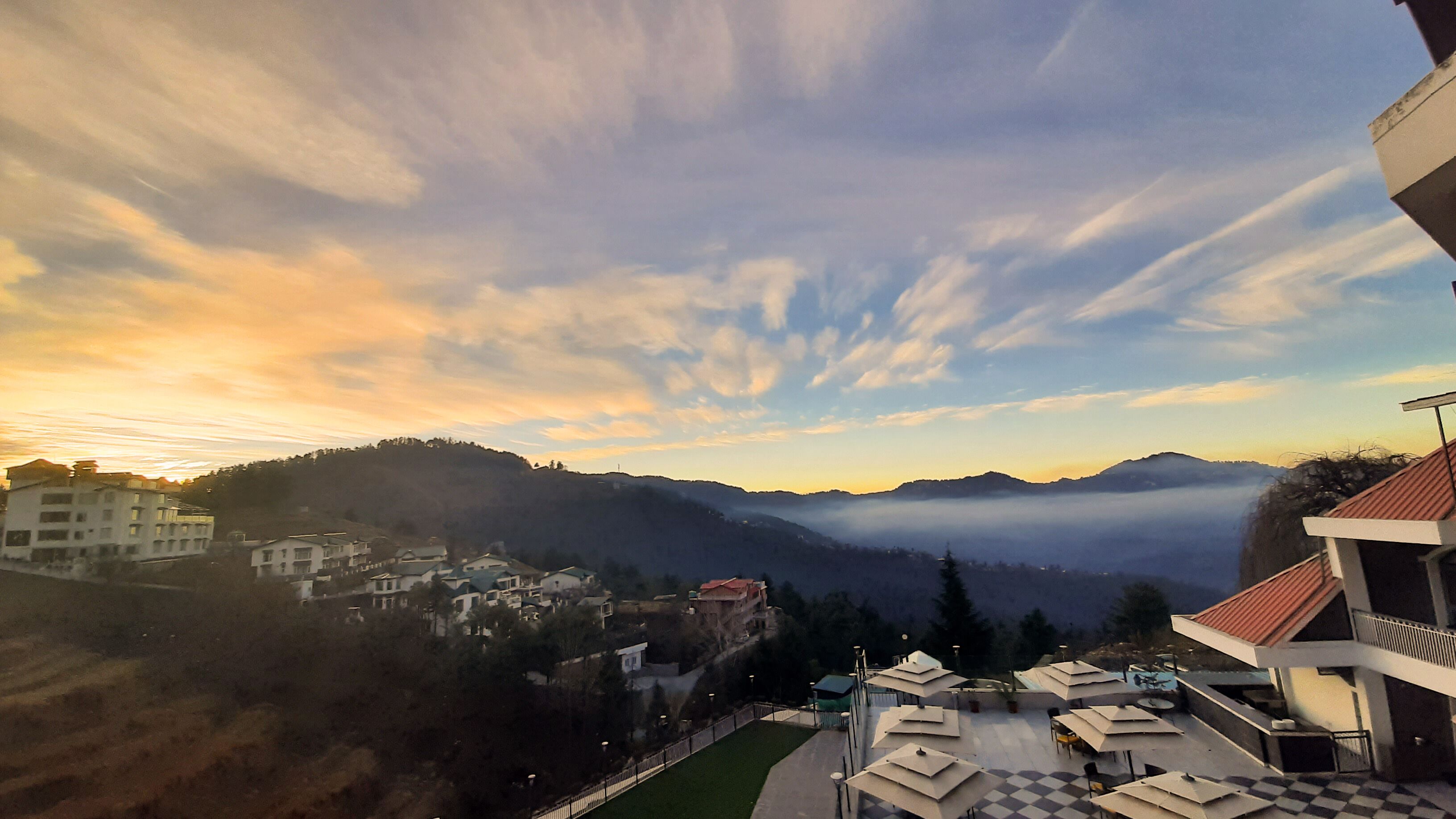 A hotel with outdoor seating and a view of the surrounding hills and mountains.