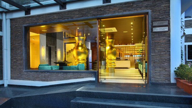 A modern building with a glass entrance, stone facade, and a staircase leading to the entrance. - Marigold Sarovar Portico , Shimla. Heated pool & AC Rooms (Resort cottage and SPA) (Shimla)