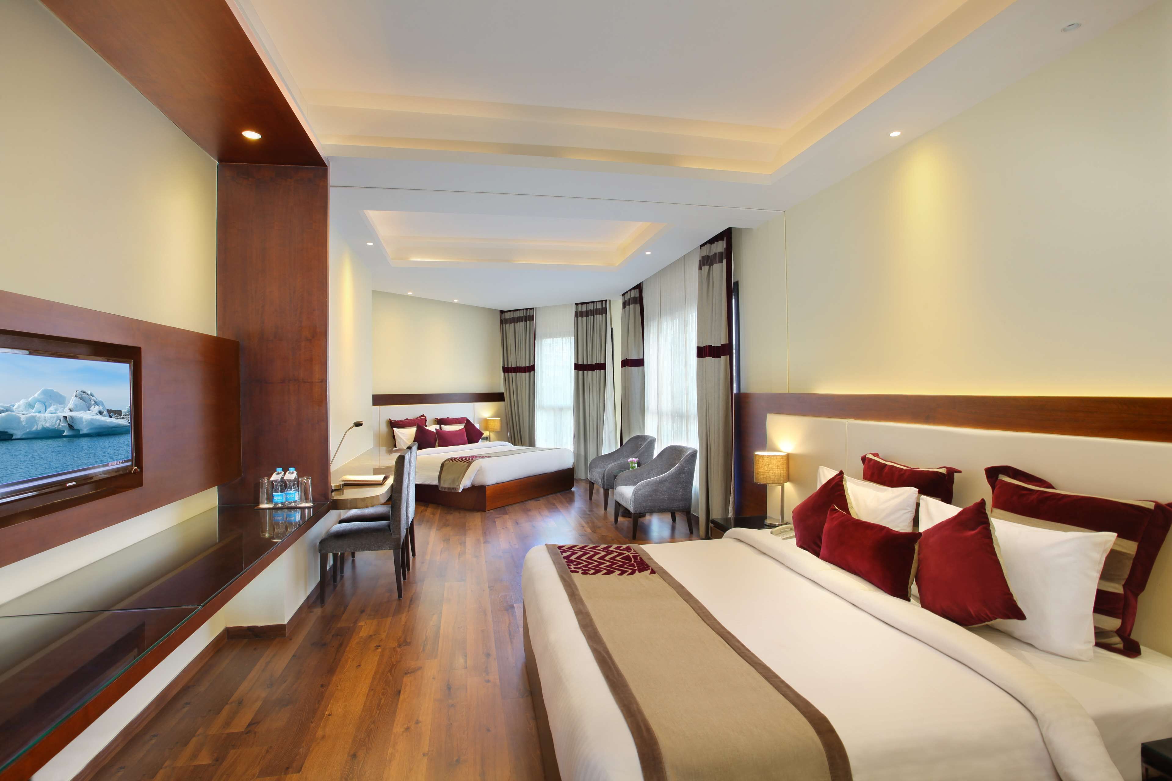 Una habitación de hotel con una cama grande, televisión, escritorio y silla.