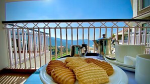 A balcony with a view of mountains, a plate of cookies, and a coffee setup. - Marigold Sarovar Portico , Shimla. Heated pool & AC Rooms (Resort cottage and SPA) (Shimla)