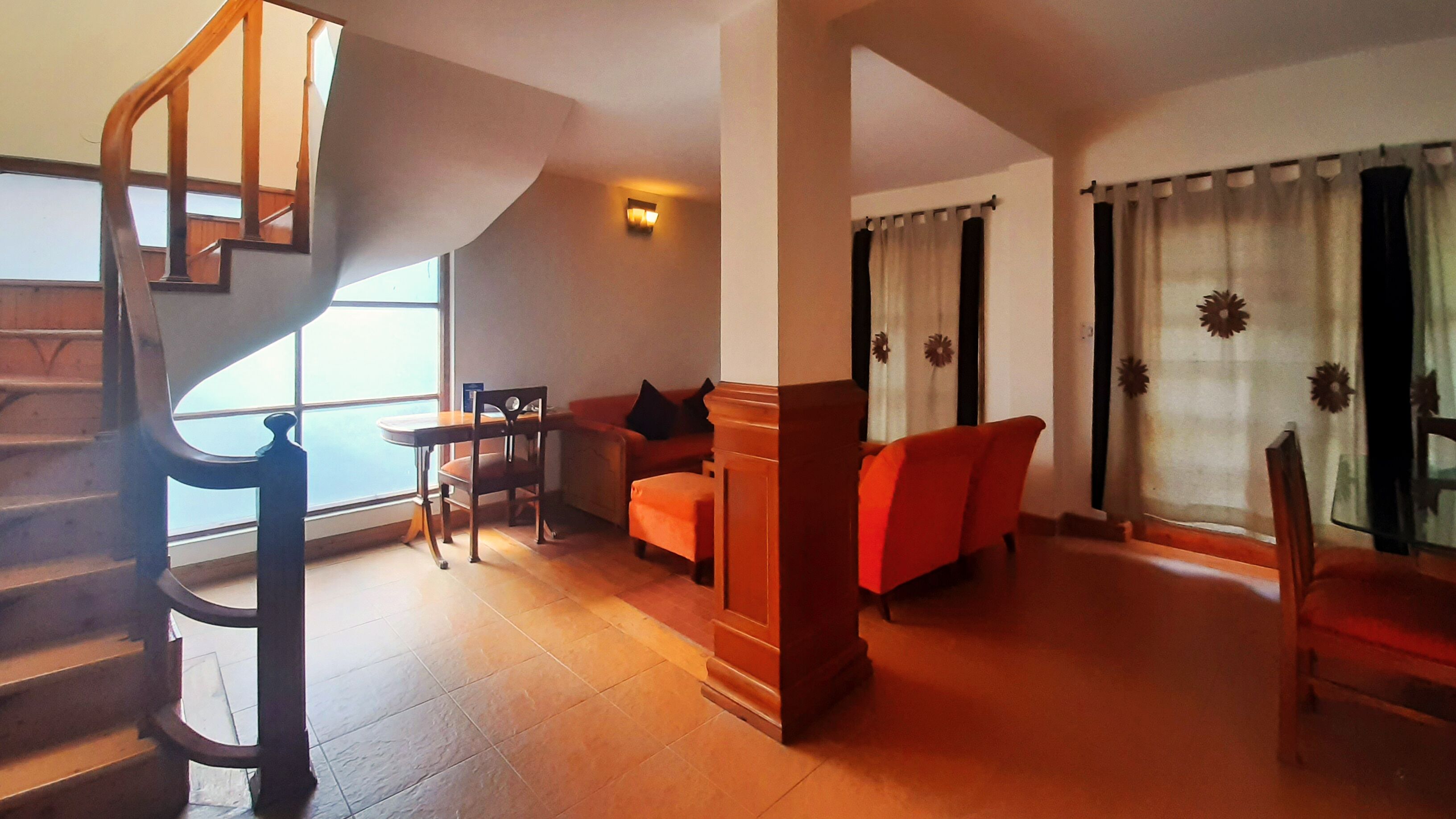 A spacious living area with a wooden staircase, a dining table, and a sofa.