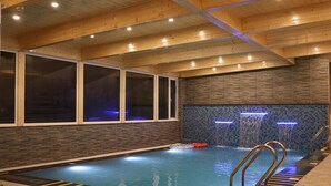 An indoor swimming pool with clear lane markings, a tiled wall with water features, and a wooden ceiling. - Marigold Sarovar Portico , Shimla. Heated pool & AC Rooms (Resort cottage and SPA) (Shimla)