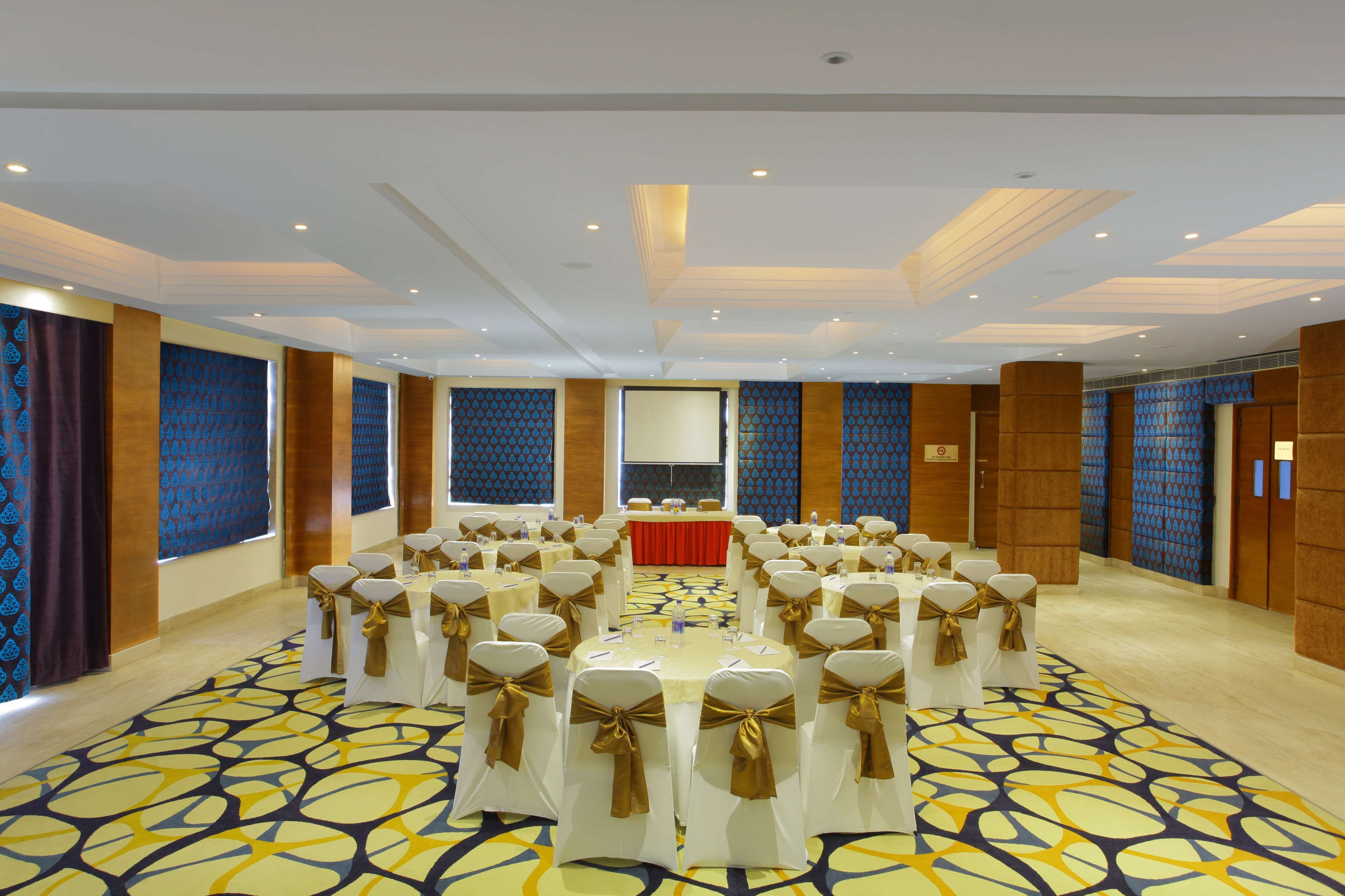 A conference room with round tables, white tablecloths, and gold sashes.