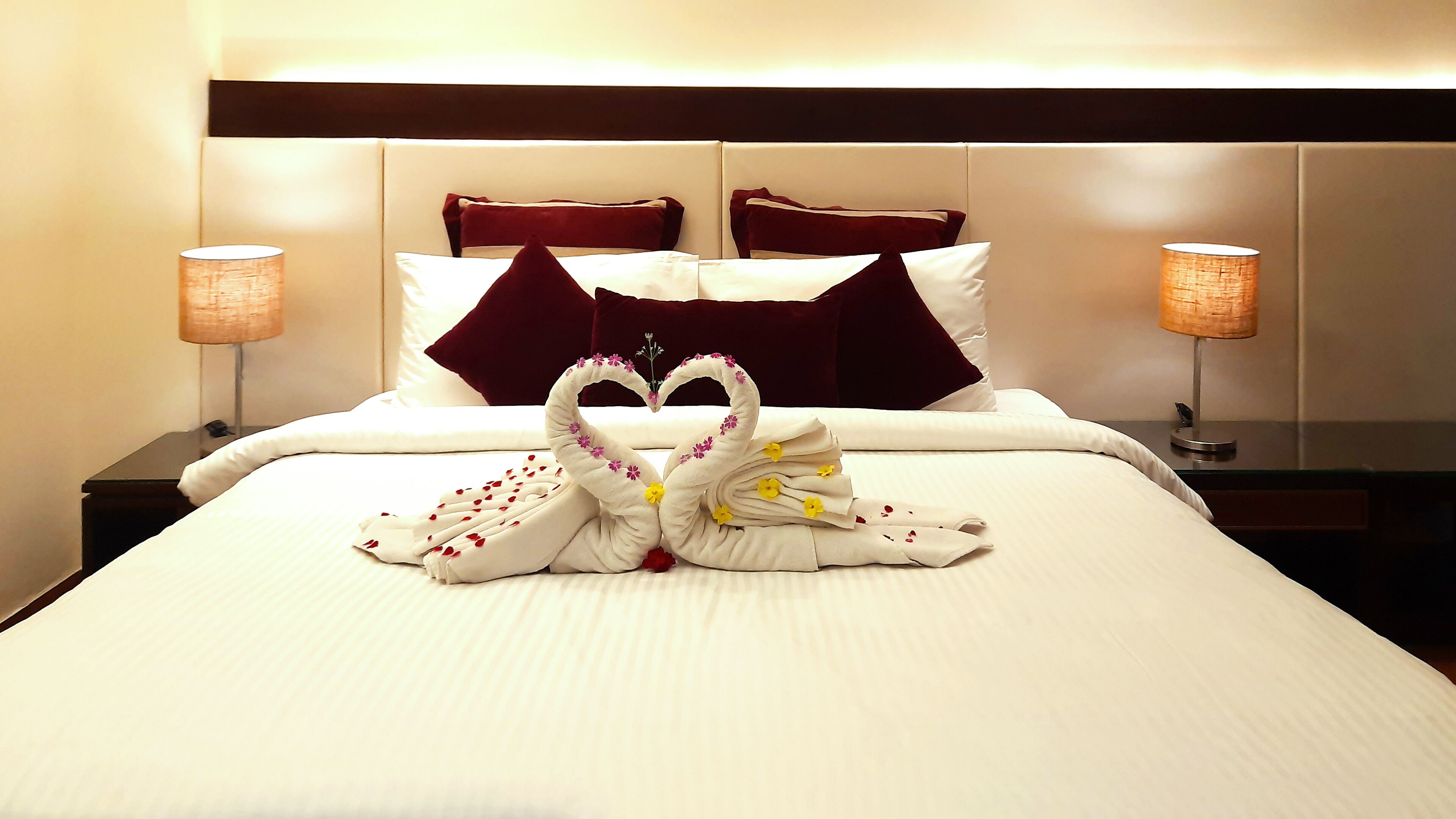 A hotel room with a neatly made bed, two nightstands, and two lamps.
