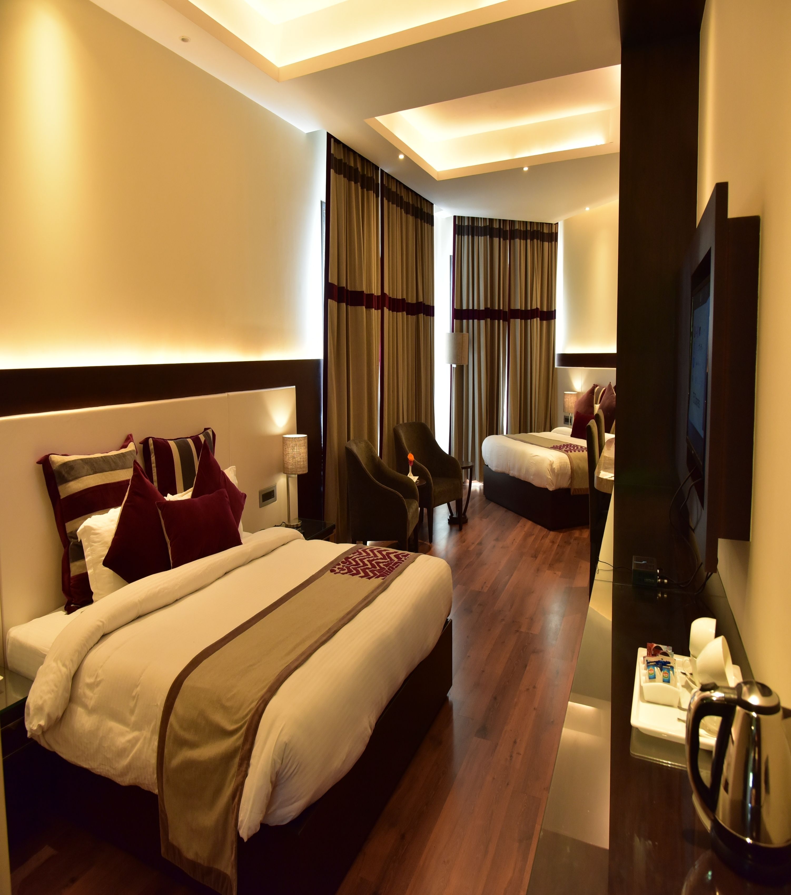 A hotel room with two beds, a TV, a coffee maker, and a desk.