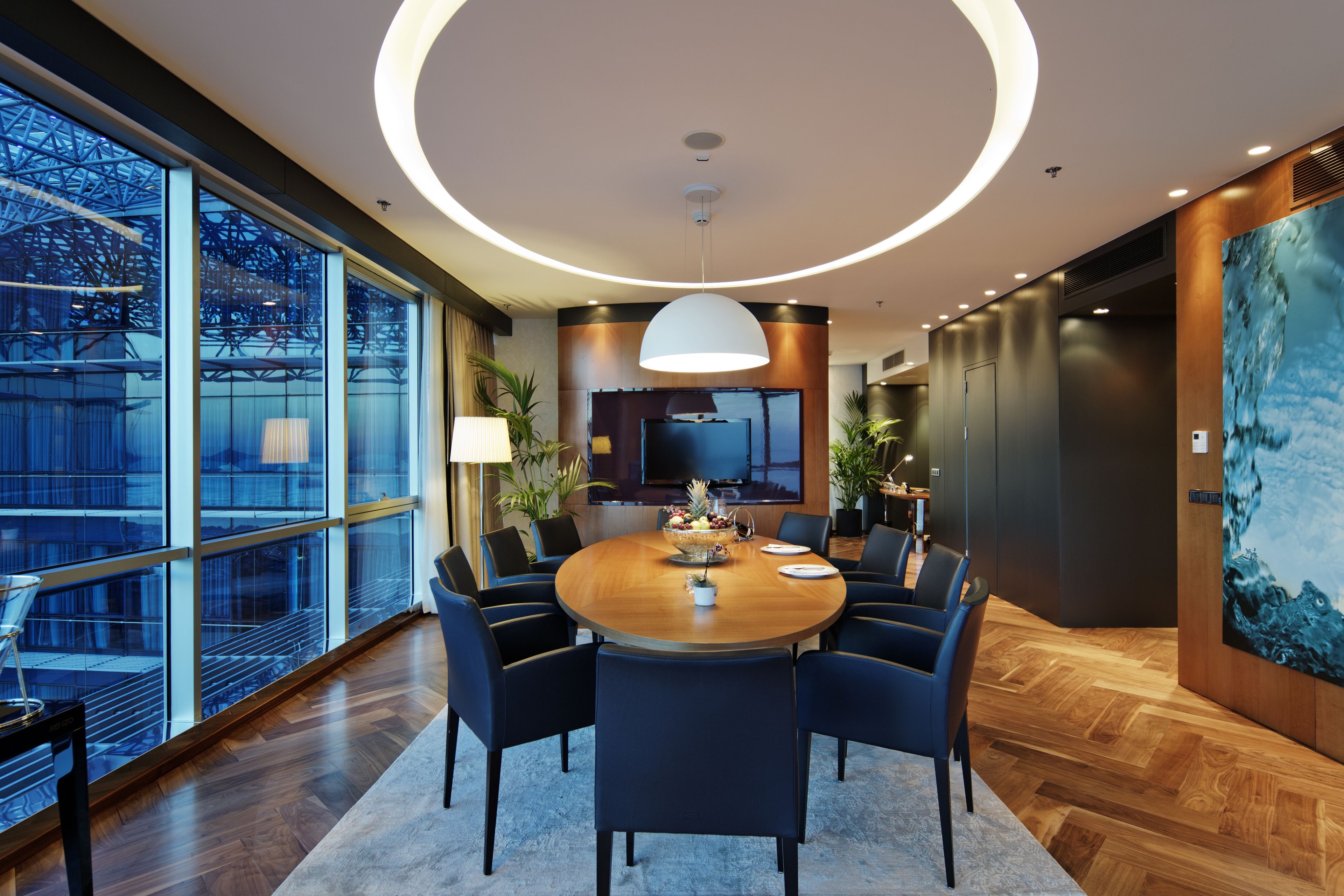 A modern dining area with a round table, chairs, and a large window.