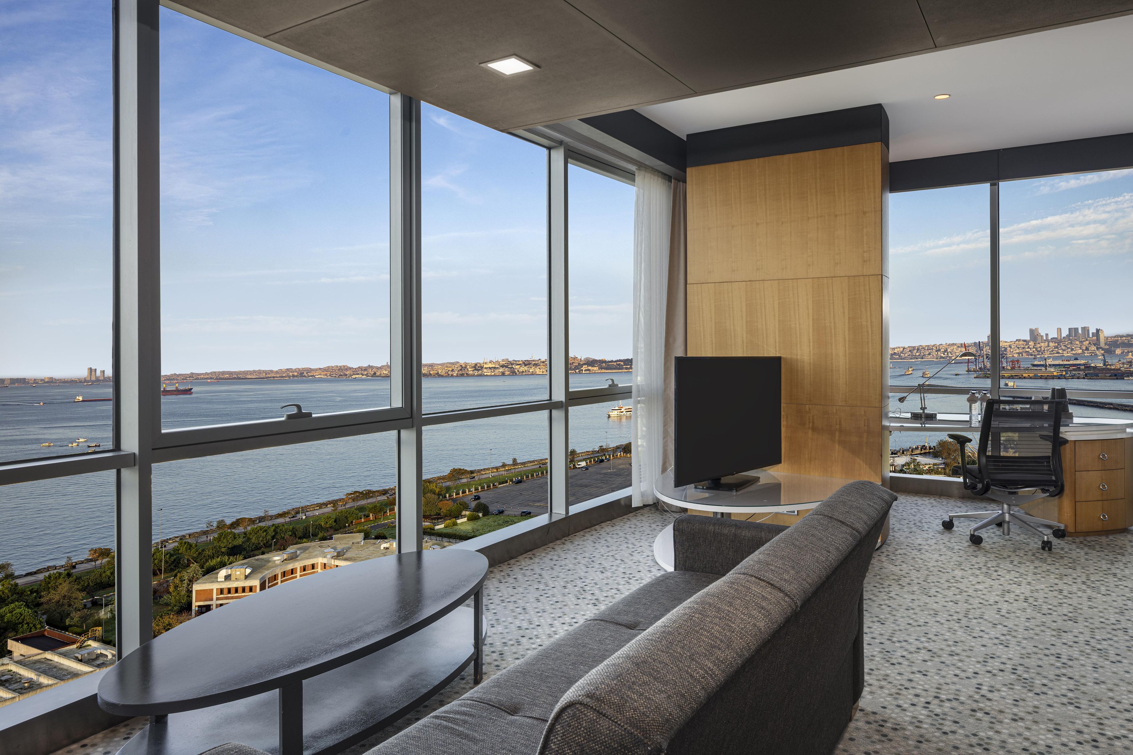 Un espacio de oficina moderno con un amplio ventanal que ofrece vistas a un paisaje urbano frente al agua.