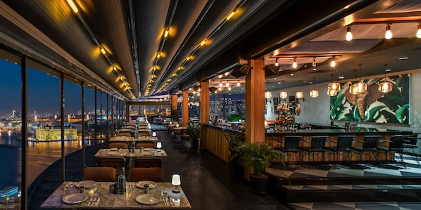 A restaurant with a city view, long tables, and a bar area. - Doubletree by Hilton Istanbul Moda (Istanbul)