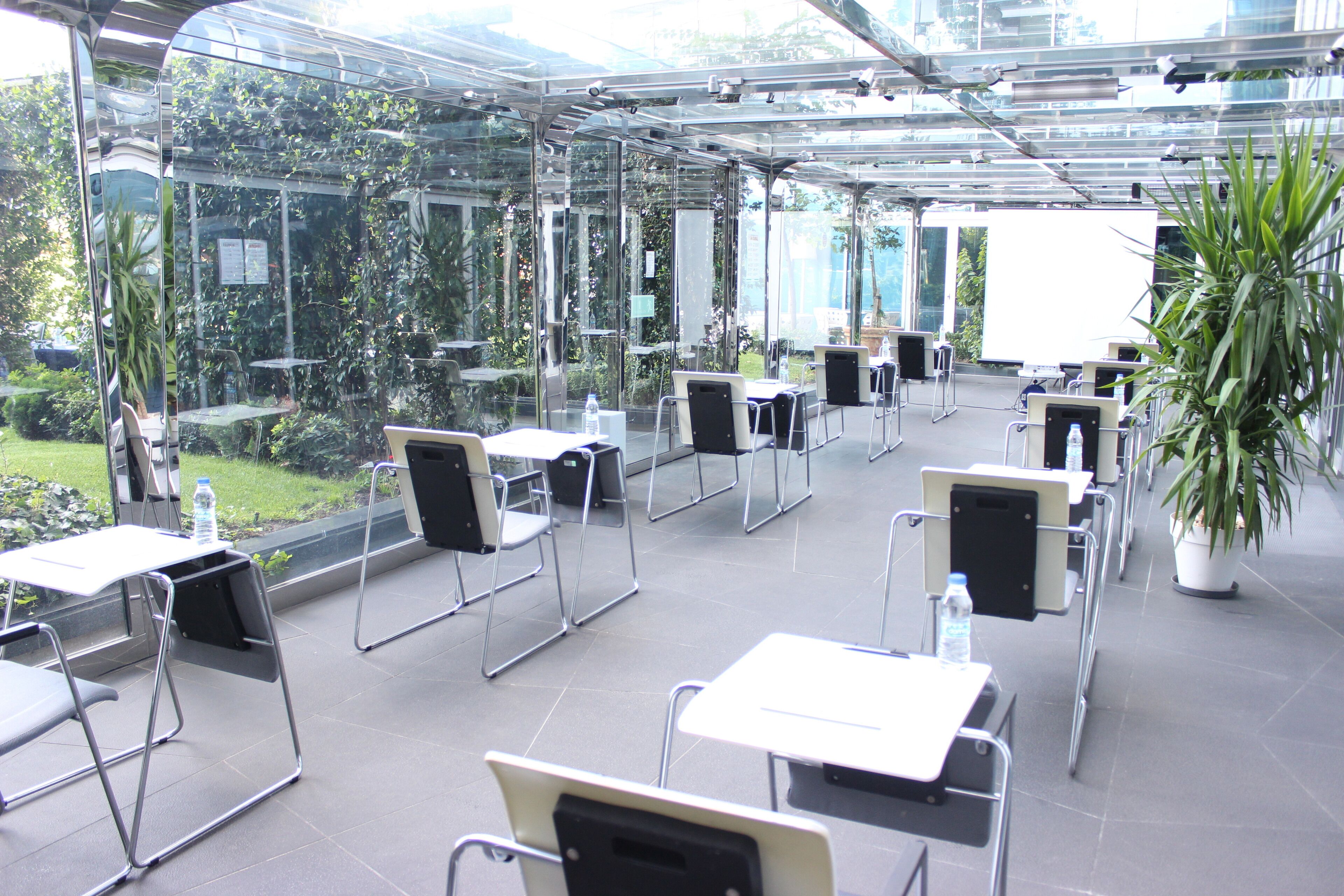 Une salle de conférence moderne avec des murs en verre, plusieurs tables et des chaises disposées pour les réunions.
