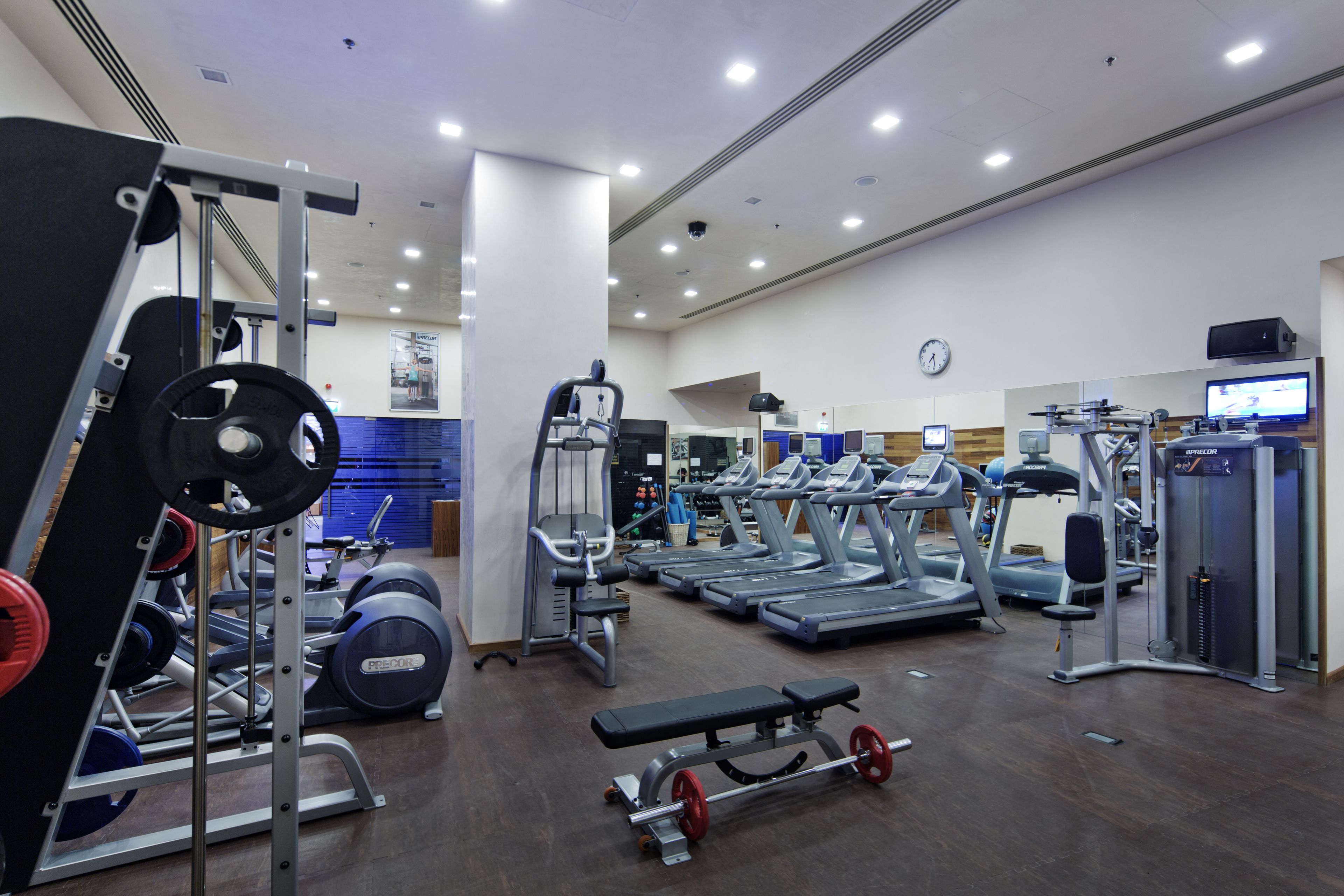 Un gimnasio con cintas de correr, máquinas de pesas y un banco.