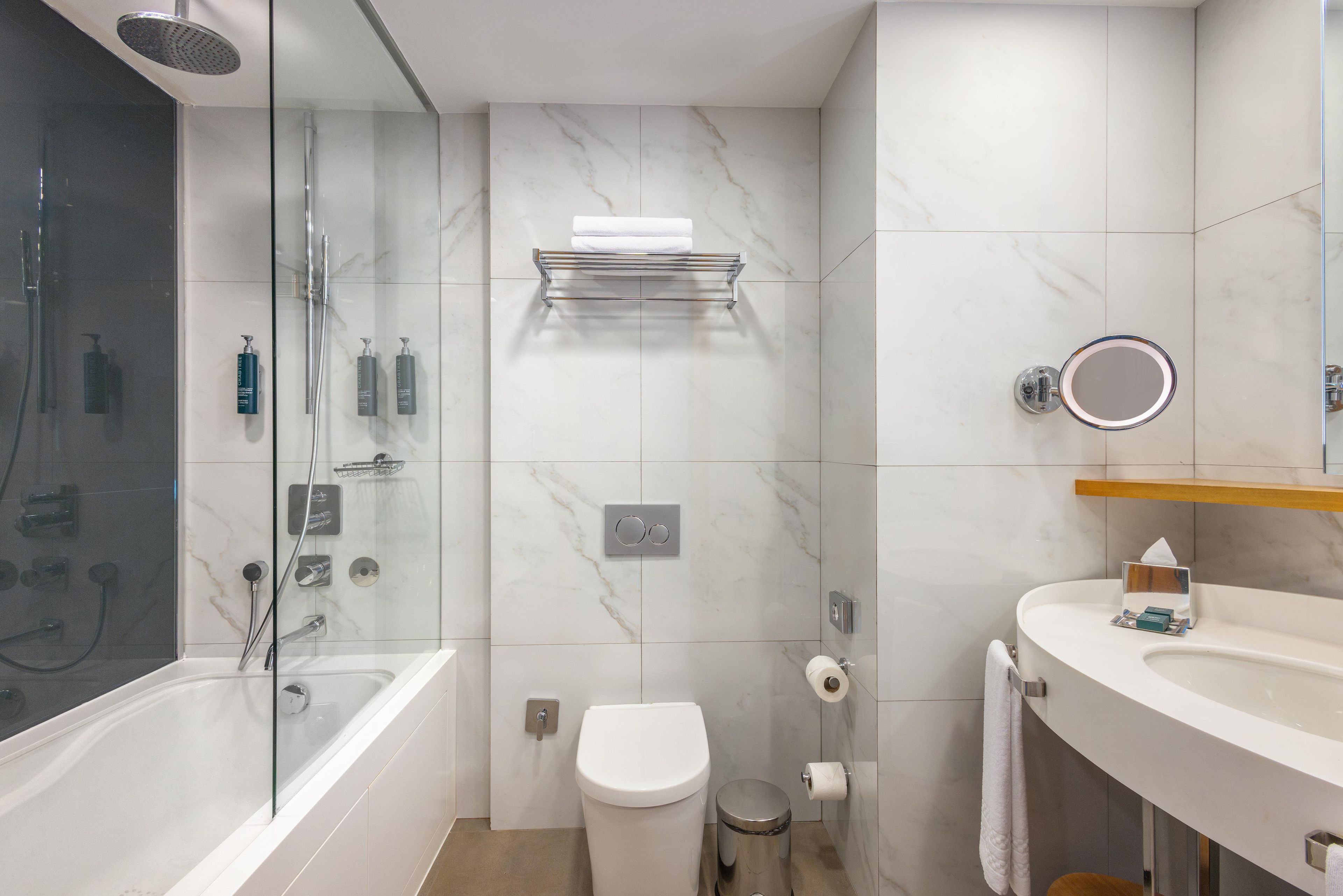 Un baño moderno con cabina de ducha de vidrio, inodoro blanco y tocador con espejo.