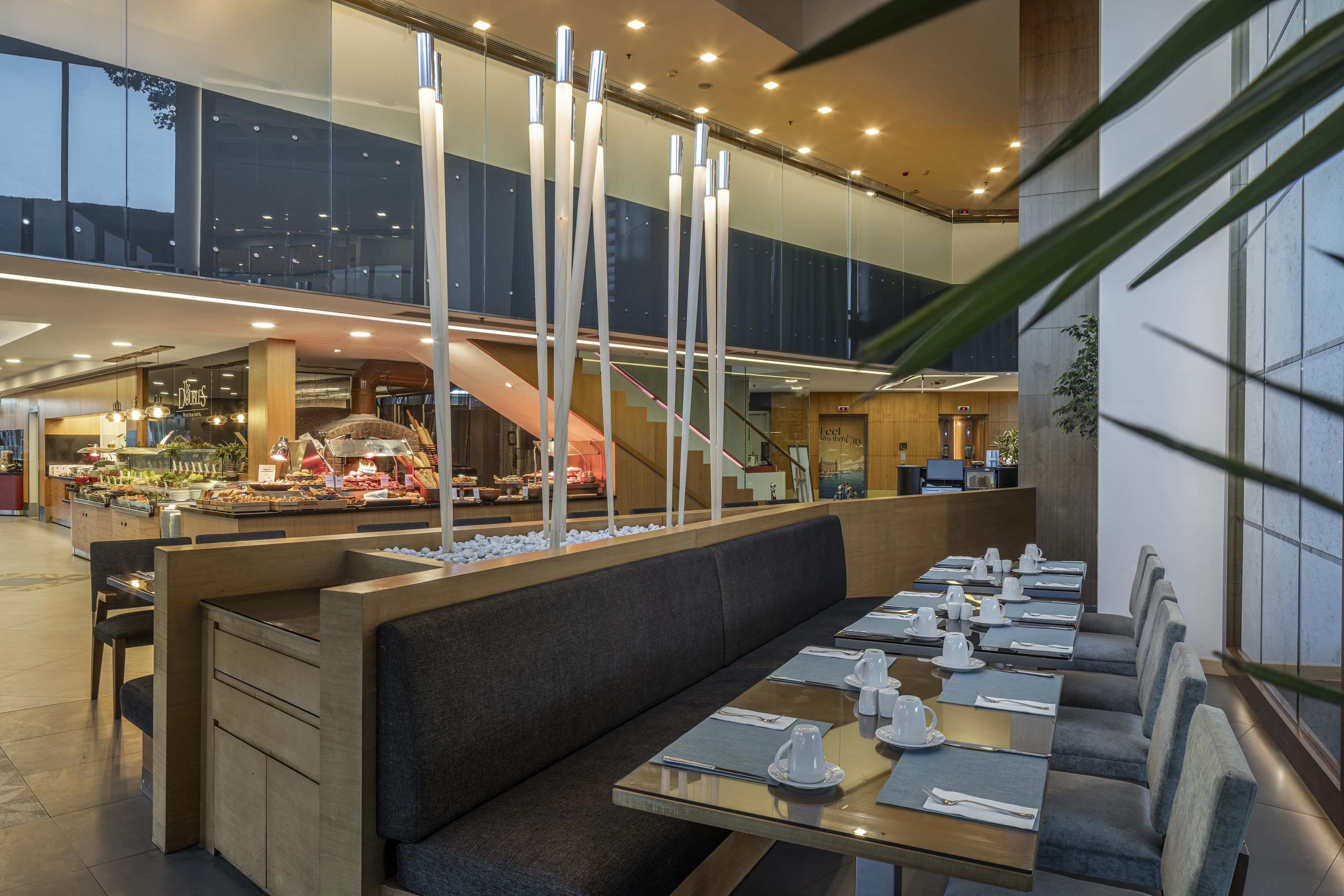 A modern restaurant with a long counter, seating area, and a buffet in the background.