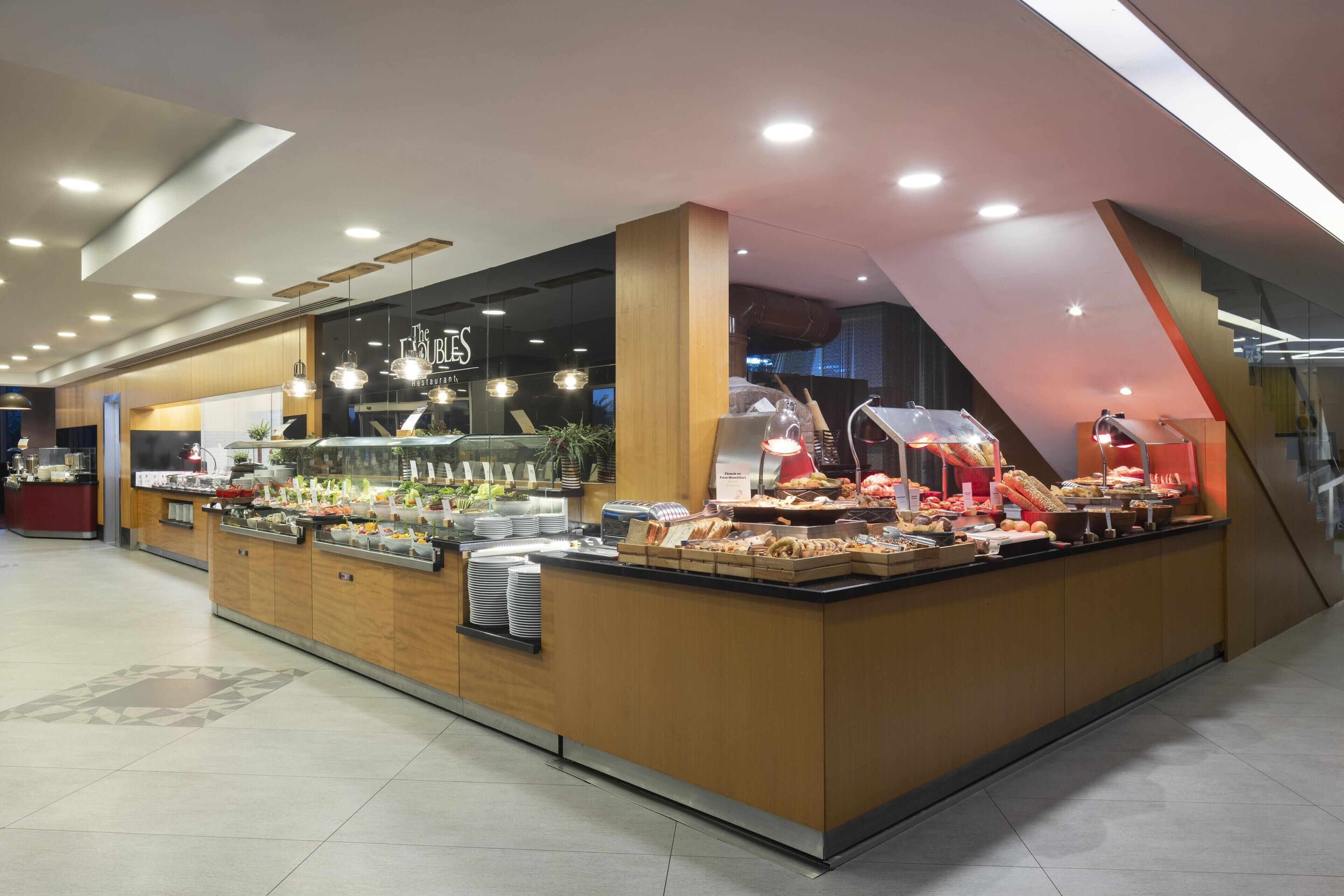 A buffet area with various food options, a counter with a menu, and a modern interior design.