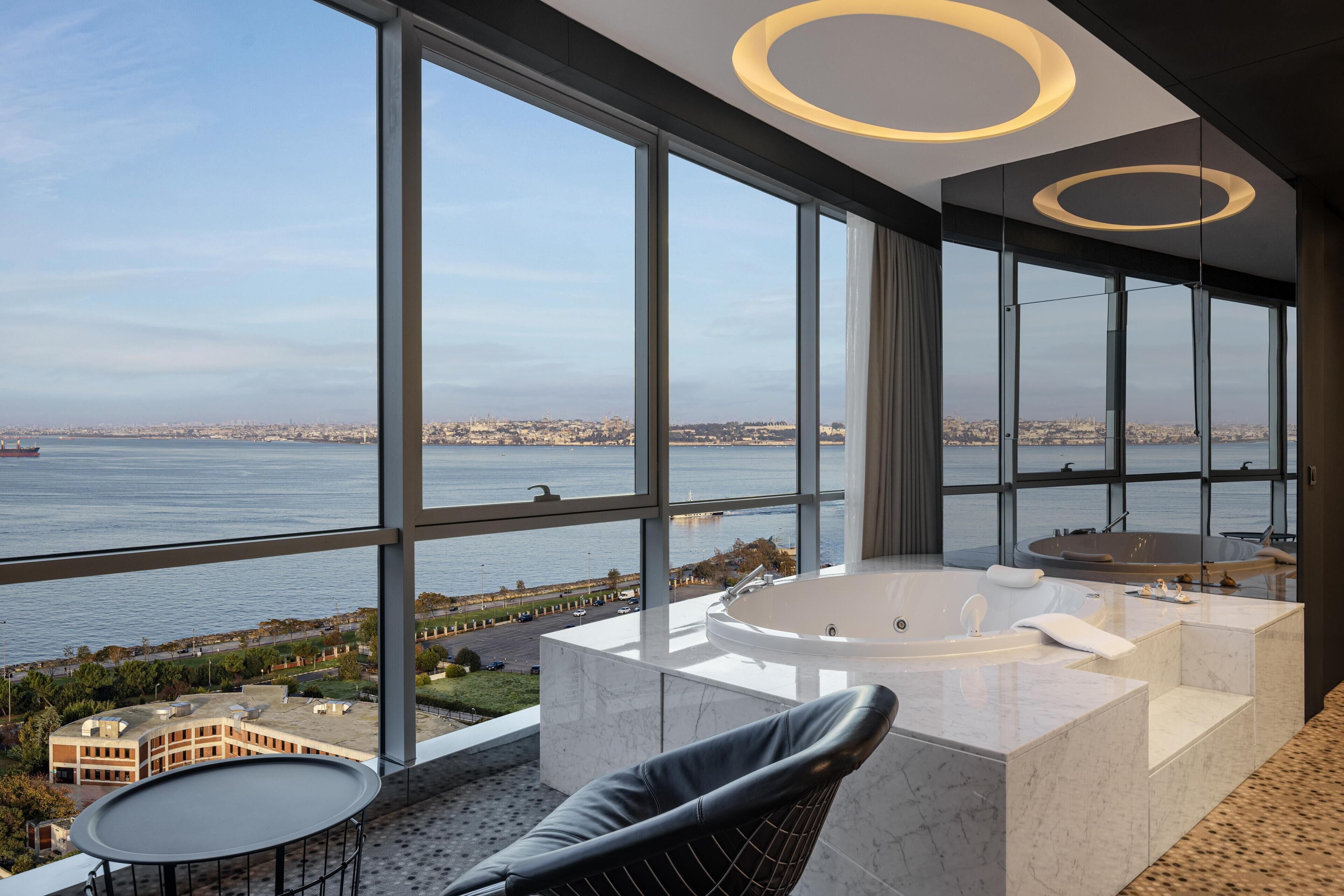 Un interior moderno con ventanas amplias, un jacuzzi y vistas a una masa de agua.
