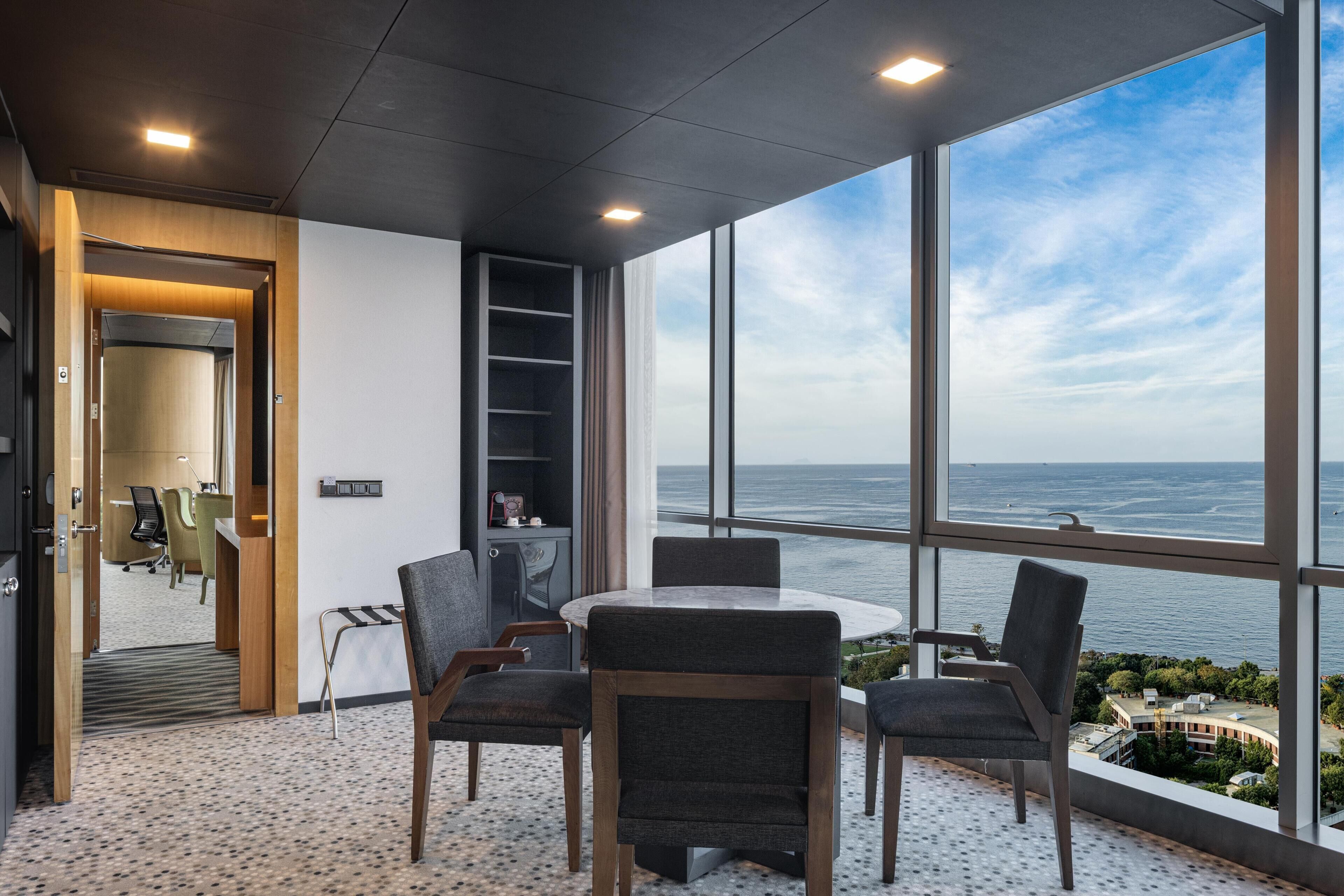 A modern room with a large window, a round table, and four chairs.