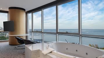 Un bagno moderno con una vasca da bagno ampia, una televisione a schermo piatto e vista sul mare.
