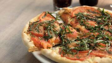 A pizza with tomato slices and herbs on a plate.